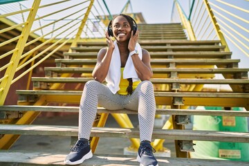 Sticker - African american woman listening to music sitting on stairs at street