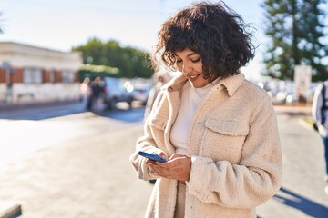 Wall Mural - Young beautiful hispanic woman smiling confident using smartphone at street