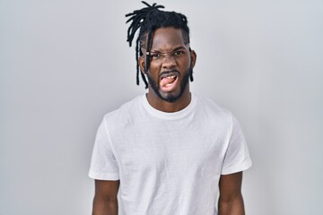 Poster - African man with dreadlocks wearing casual t shirt over white background sticking tongue out happy with funny expression. emotion concept.