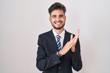 Poster - Young hispanic man with tattoos wearing business suit and tie clapping and applauding happy and joyful, smiling proud hands together