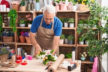 Canvas Print - Middle age grey-haired man florist make bouquet of flowers at florist