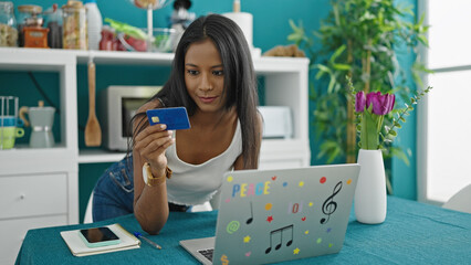 Wall Mural - African american woman shopping with laptop and credit card sitting on table at dinning room