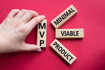 MVP - Most Valuable Player symbol. Wooden cubes with words MVP. Businessman hand. Beautiful red background. Business and MVP concept. Copy space.