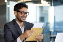 Young Successful Arab Businessman At Workplace Inside Office, Man Smiling Satisfied Received Mail Letter Envelope Notification Message With Good News, Boss In Business Suit.