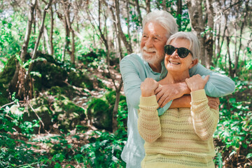 Portrait of bonding senior family couple hugging in outdoors enjoying mountain hike in the woods appreciating nature and freedom, retired seniors man and woman and healthy lifestyle concept