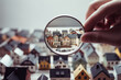 A hand holding a magnifying glass over a small town, emphasizing the importance of real estate
