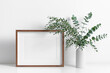 © nikavera - Wooden frame mockup in white interior with fresh eucalyptus plant