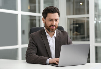 Wall Mural - Man working on laptop at white desk in office