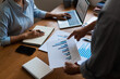© snowing12 - Close up of businessman pointing on chart of financial document and businesswoman typing on laptop