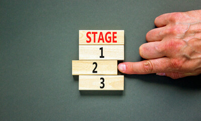 Time to stage 2 symbol. Concept word Stage 1 2 3 on wooden block. Businessman hand. Beautiful grey table grey background. Business planning and time to stage 2 concept. Copy space.