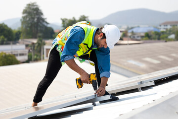 Electrical engineering man using electric hand drill to Installing Solar Cell panels on Roof. Solar energy clean and green alternative energy concept