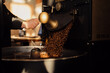 Crop anonymous male worker pressing lever and roasted coffee beans pouring from release chute in modern factory