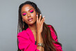 Fashion Portrait Black Woman in Pink clothes. Fashion Makeup curly hair and braids, lip gloss. Luxury Fashion model African American posing in studio, gray wall. beautiful black woman looking down    