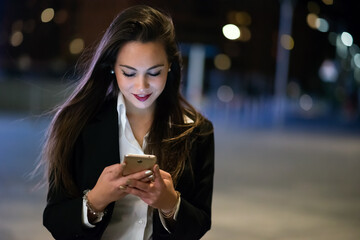 Woman using her cellphone at night in a city