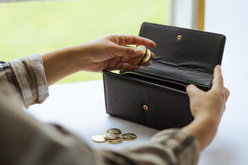 Woman keeps money in her wallet. Coins of ten Mexican pesos. Savings and economy in Mexico