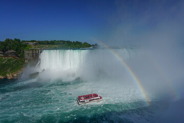 Wall Mural - Niagara Falls, Ontario, Canada: A double rainbow appears over the Niagara River as a tour boat takes visitors to the foot of the Horseshoe Falls.