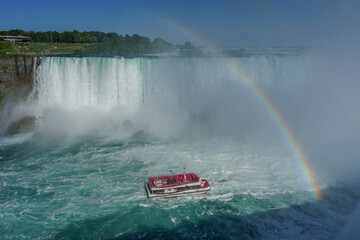 Wall Mural - Niagara Falls, Ontario, Canada: A rainbow appears over the Niagara River as a tour boat takes visitors to the foot of the Horseshoe Falls.