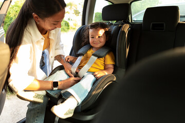 Wall Mural - Chinese Mom Ensuring Safety Securing Toddler Daughter in Car Seat