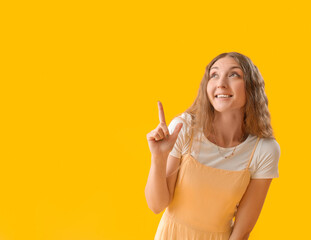 Sticker - Beautiful young woman pointing at something on yellow background