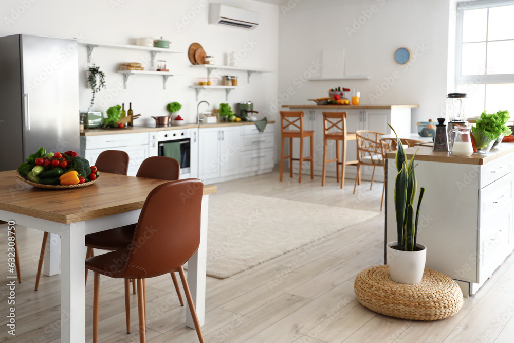 Interior of light kitchen with counters, dining table and healthy food