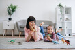 © sofiko14 - Portrait of mother-daughter duo posing with amazing toys of extinct reptiles in hands while lying comfortably on floor. Smiling caucasian ladies gaining knowledge about different animals and habitats.