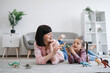 © sofiko14 - Playful tween girl with animal toy having fun with brunette woman in living room of spacious apartment. Mindful mother encouraging scientific exploration while keeping daughter entertained indoors.