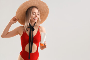 Wall Mural - Young woman with sunscreen cream on light background