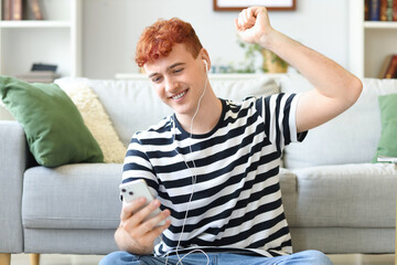 Poster - Young redhead man in earphones with mobile phone listening to music at home