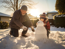 Grandfather And Grandchild Building A Snowman Together