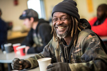 Positive Black Homeless Man Sits At A Table In A Bustling Shelter Dining Hall, Surrounded By Other Individuals