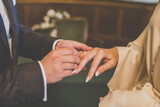 Fototapeta  - Pan młody zakłada Pani młodej pierścionek na palec. Ślub w urzędzie. Obrączka na palcu. The groom puts a ring on the bride's finger. Wedding at the office. A ring on a finger.