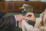 Fototapeta  - Pan młody zakłada Pani młodej pierścionek na palec. Ślub w urzędzie. Obrączka na palcu. The groom puts a ring on the bride's finger. Wedding at the office. A ring on a finger.
