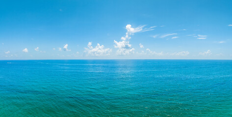 panoramic drone view of ocean with clouds in blue sky