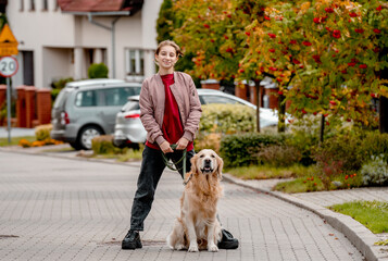 Sticker - Preteen teen girl in pink jacket with golden retriever dog on lace looking at camera. Female child kid with a purebred labrador doggy pet