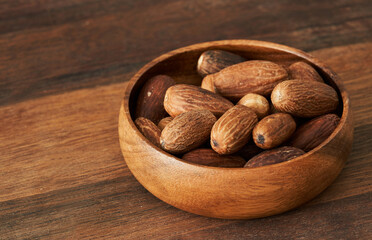 nutmeg whole muscat nut in wood bowl on wooden table background. nutmeg whole muscat nut. pile of nutmeg whole muscat nut food background                                           