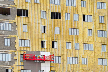 Poster - External wall thermal insulation with mineral wool. Passive heat insulation with rock wool. Insulation facade of multistory residential building. Energy efficiency. Worker in suspended platform