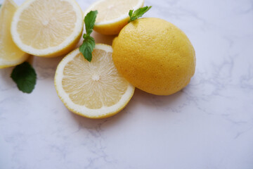 Wall Mural - Fresh lemons and green mint composition on white marble background. Fresh tropical fruits. Slice lemon fruits.