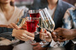 © Seventyfour - Focus on flutes with fizzy champagne and wineglasses with red wine held by young intercultural friends during celebration of holiday or life event