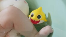 A Rubber Yellow Shark Doll In A Bathtub With A Newborn Baby. A Child In. A Bathtub With A Toy Fish.