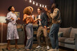 © Seventyfour - Group of happy young friends in casualewar dancing together while enjoying home party in living room illuminated by row of lamps