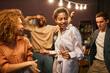 © Seventyfour - Young smiling African American woman dancing among her friends and enjoying home party while clubbing against excited black man