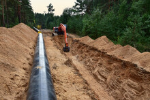 Natural Gas Pipeline Construction. Excavator Dig Trench At Forest. Backgoe On Earthwork For Laying Crude Oil And Natural Gas Pipeline. Water Main Pipes Sewer And Underground Storm Sewer Pipe.