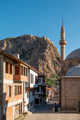 Sticker - Traditional Turkish Ottoman houses in Afyonkarahisar Turkey. Afyon Castle on the rock and Mevlevihane Museum in front of it