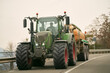 © AlexGo - Agricultural Efforts in Motion. A Tractor at Work on a Sunny Summer Day. Farm tractor moving on the rural road near the farm