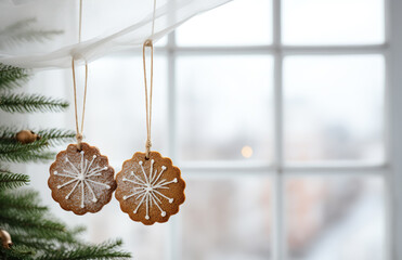 Gingerbread gingerbread hanging from a string as Christmas decorations against a blurred window background.