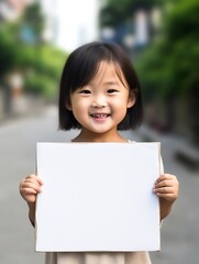 Wall Mural - Generative AI : Young little asian girl or kid enjoy holding empty white placard board for media banner business content presentation mock up blank sign for message with positive and fun in creative d