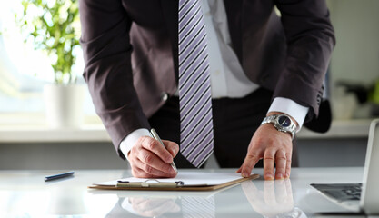 Male arm in suit and tie fill form clipped to pad with silver pen closeup. Sign gesture read pact sale agent bank job make note loan credit mortgage investment finance executive chief legal law