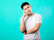 © Daniel - A portrait of an Asian man wearing a white t-shirt, posing as if thinking with his hand on his chin, isolated with a turquoise background.