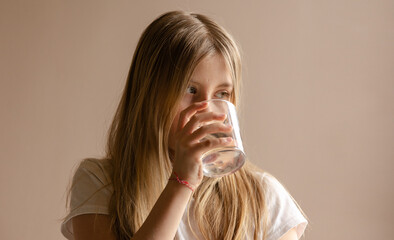 blonde girl drink a glass of water at home close up