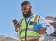 © Tamline L/peopleimages.com - Black man, online or architect with phone on construction site for building update, social media or networking. Smile, news or happy African engineer texting to chat on digital mobile app on Internet